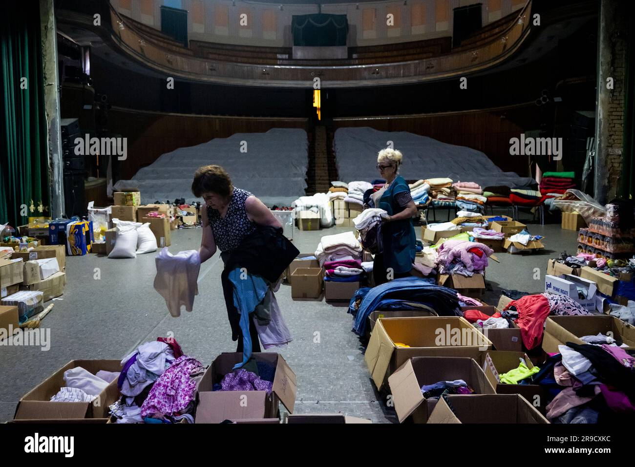 Cherson, Ukraine. 24. Juni 2023. Eine Frau sortierte humanitäre Hilfe für die von der Flut betroffenen Menschen im Kherson Musik- und Drama-Theater von Mykola Kulish in einem Bombenbunker in Kherson, Ukraine, am 24. Juni 2023. Der Kakhovka-Staudamm in der Ukraine wurde in den frühen Morgenstunden des 6. Juni 2023 zerstört und verursachte umfangreiche Überschwemmungen entlang des unteren Dnieper-Flusses in der Oblast Kherson. Kredit: Ondrej Deml/CTK Photo/Alamy Live News Stockfoto