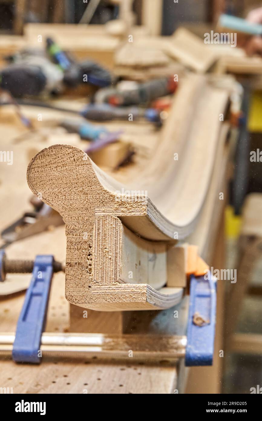 Gebogener Handlauf aus Holztreppe aus Eichenbohlen und Sperrholz auf Tischnaht. Detaildarstellung des Treppenzauns in der Zimmereiwerkstatt Stockfoto