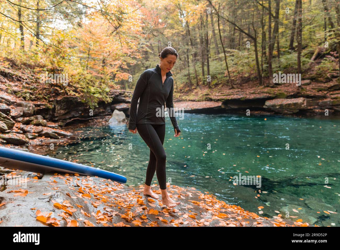 Eine Frau, die in einer Herbstszene am Fluss läuft Stockfoto