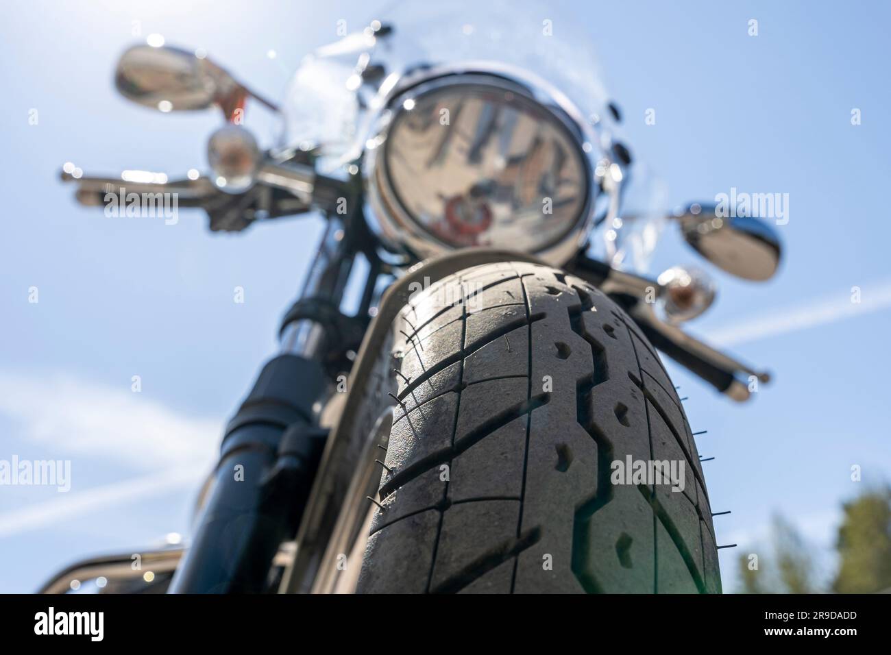 Motorrad auf blauem Himmelshintergrund. Der vordere Teil eines klassischen Motorrads mit rundem Scheinwerfer, Windschutzscheibe und Spiegeln. Der Weg der Freiheit Stockfoto