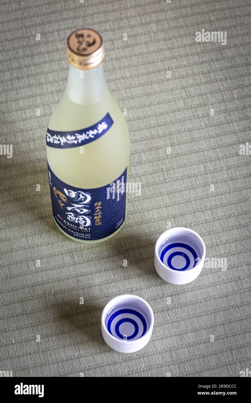 Sake-Becher und -Flasche auf Tatami-Matten, Sake ist ein japanischer Likör aus fermentiertem Reis. Stockfoto