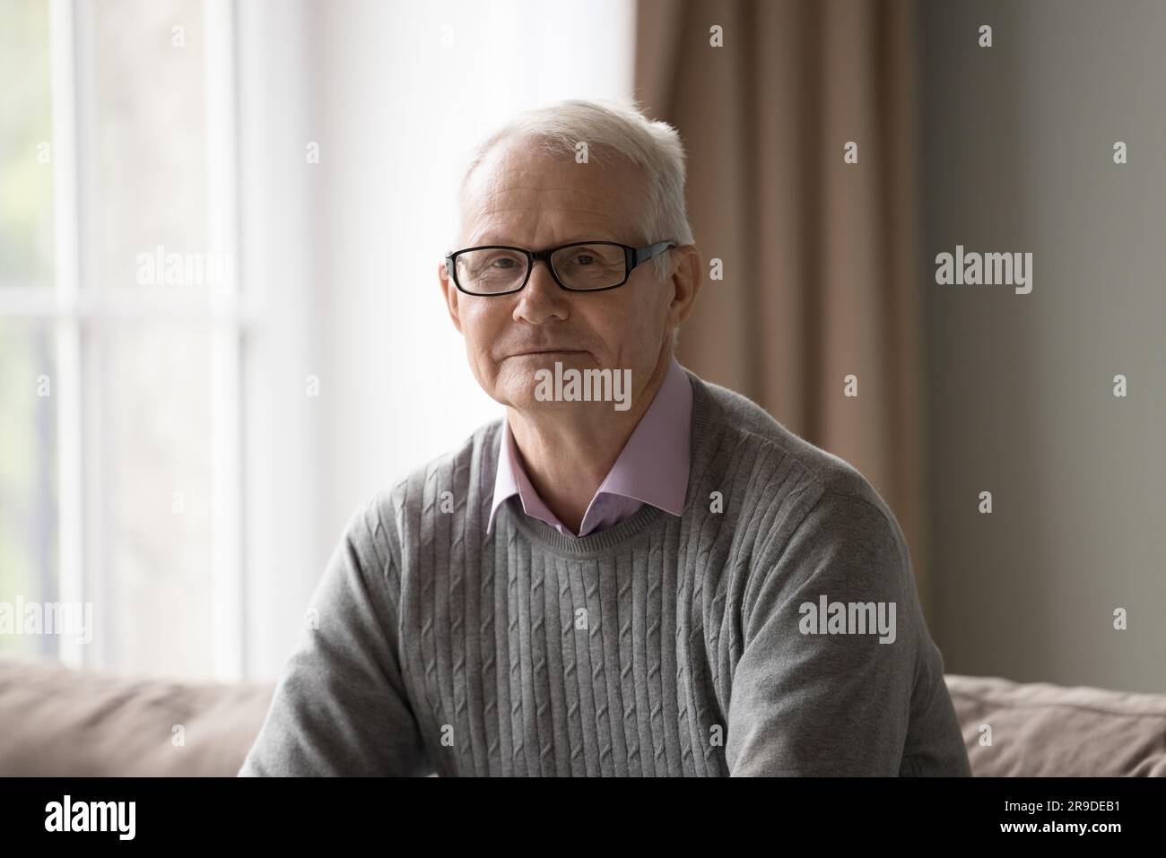 Porträt mit Kopfschuss reifer Mann mit Brille sitzt auf der Couch Stockfoto