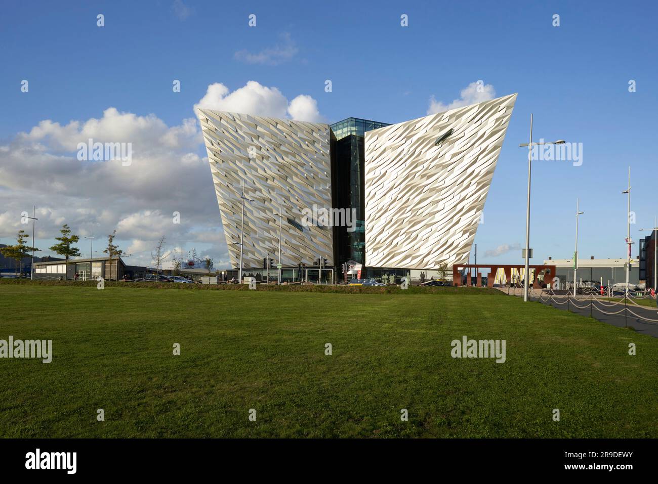 Museumseingang auf der anderen Seite des Rasens. Titanic Belfast, Belfast, Vereinigtes Königreich. Architekt: Eric Kuhne, 2012. Stockfoto