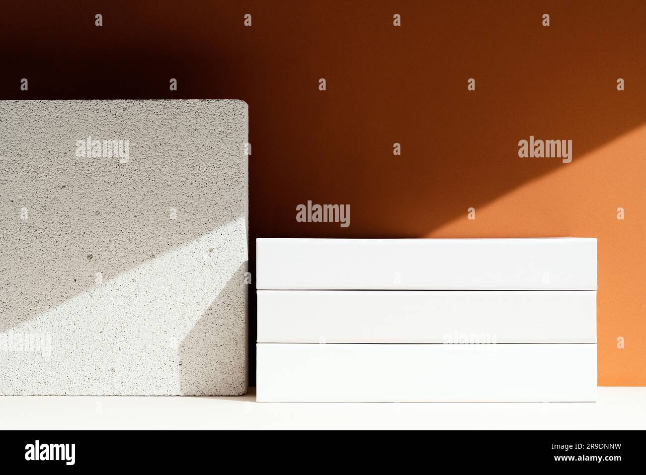 Leeres Weißbuch-Stapelmodell auf braunem Hintergrund. Sonne und Schatten, Schatten auf braunem Hintergrund. Stockfoto