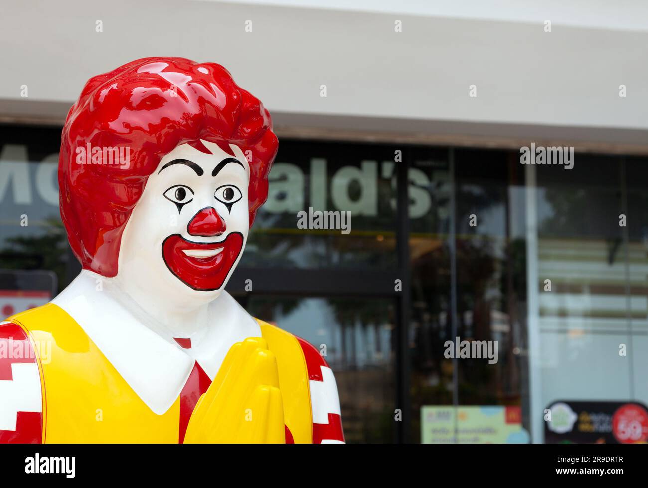 Die Plastikstatue Ronald McDonald begrüßt die Gäste mit einer persönlichen Geste vor dem McDonalds Restaurant. Fastfood-Kette farbenfrohes Maskottchen trifft Klien Stockfoto