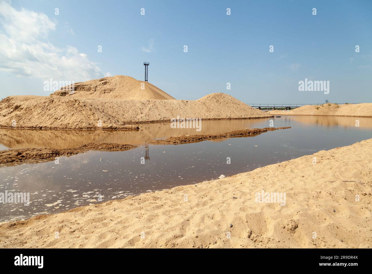 Riesige Sandhaufen am blauen Himmel. Sandabbaugrube. Wunderschöne sonnige Industrielandschaft Stockfoto