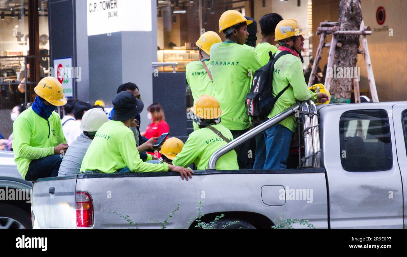Bauarbeiter, die Schutzhelme tragen, reisen in der Stoßzeit nach der Arbeit auf der Silom Road, Bangkok, Thailand, stehend oder auf dem Rücksitz eines Lkws nach Hause. Obwohl dies 2017 aus Sicherheitsgründen illegal wurde, ist dies nach wie vor eine gängige und wirtschaftliche Art, in Thailand zu reisen. Stockfoto
