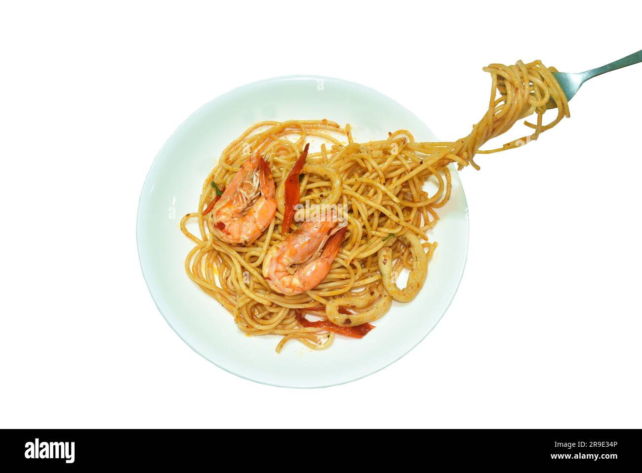 Gebratene scharfe Spaghetti-Meeresfrüchte mit Basilikumblättern in Shrimps mit Chilipasten und Tintenfisch auf einem Teller, der von einer Gabel gerollt wird Stockfoto