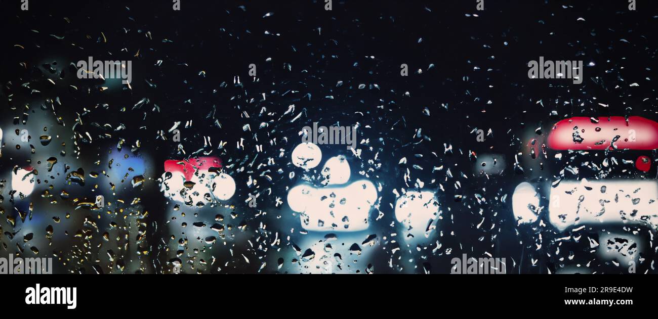 Fahren bei Regen. Regen auf der Windschutzscheibe oder auf dem Autofenster in der Regenzeit und unscharfe Straße im Hintergrund. Regentropfen auf dem Spiegel. Straße bei Regen Stockfoto