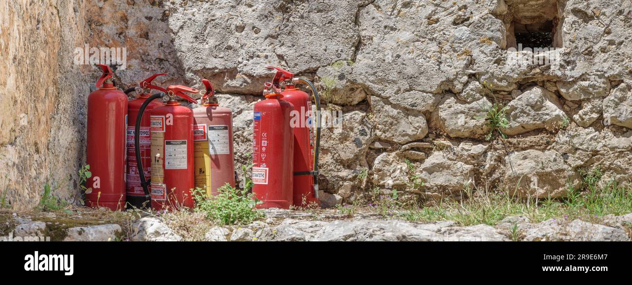 Eine Sammlung von Feuerlöschern, die draußen an einer Steinmauer stehen Stockfoto