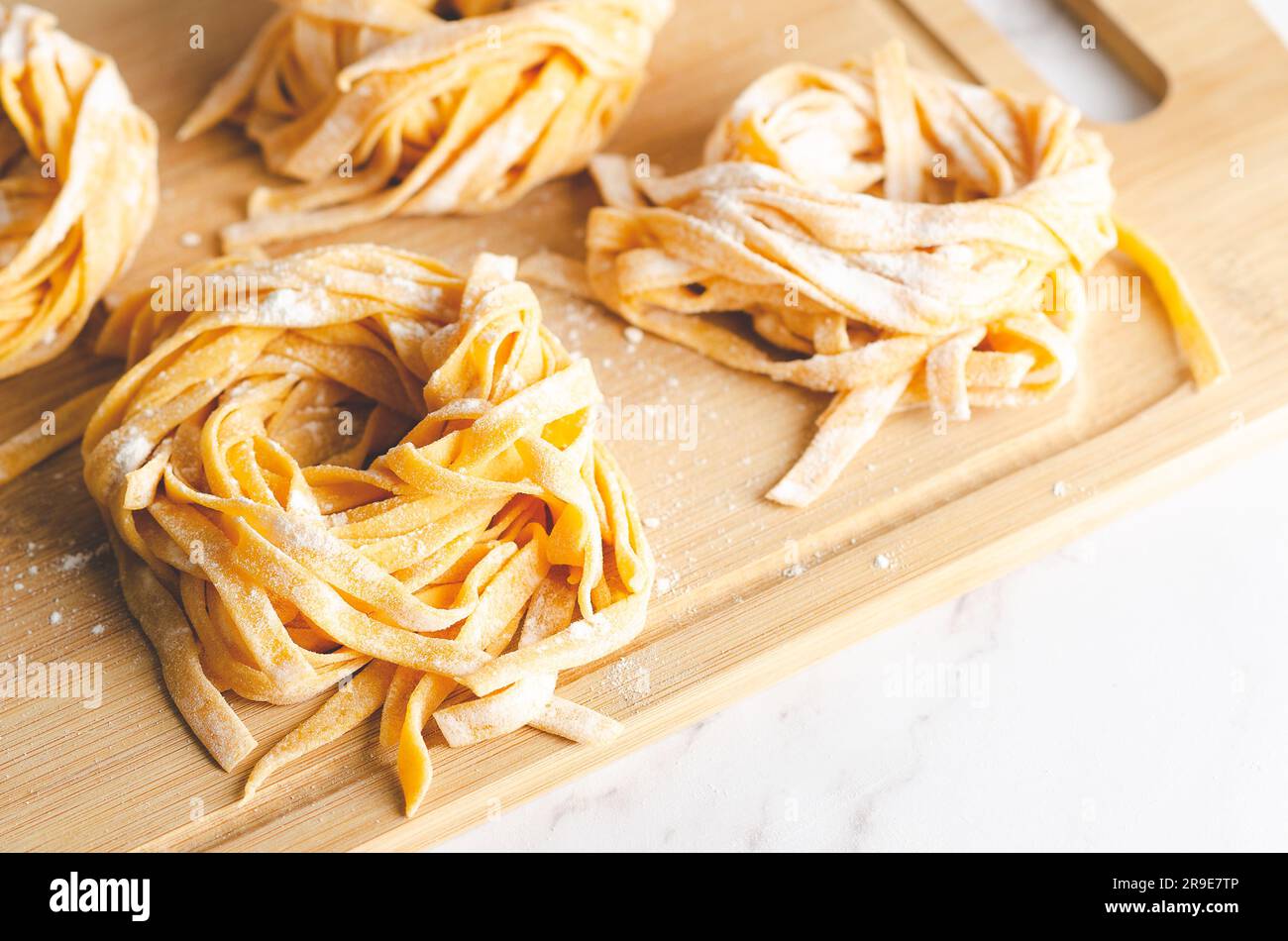 Butternusskürbis-Nudeln nisten auf einem Holzbrett auf Marmorhintergrund. Stockfoto