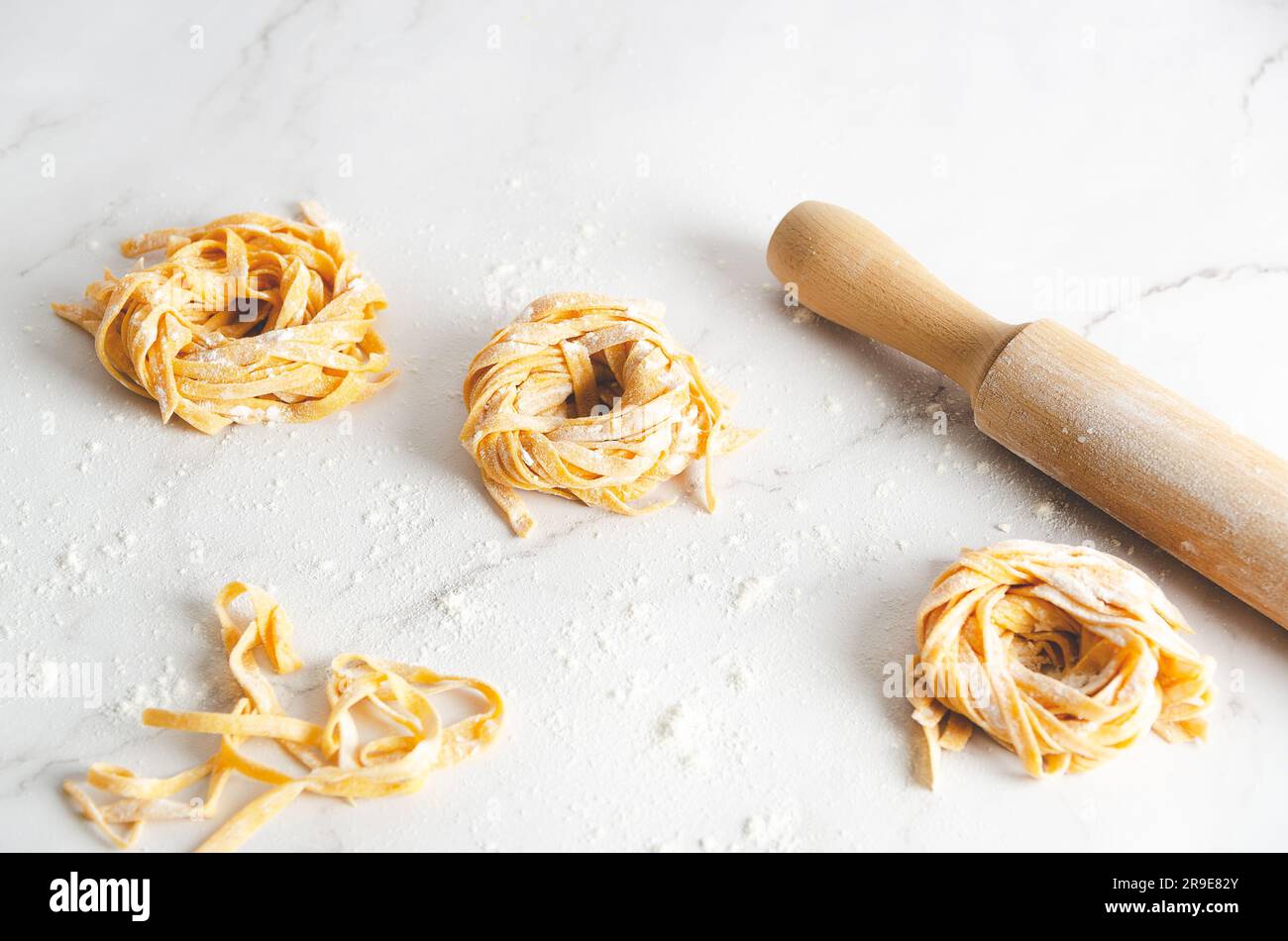 Butternusskürbis-Nudelnester und eine rollende Nadel auf Marmorhintergrund. Stockfoto