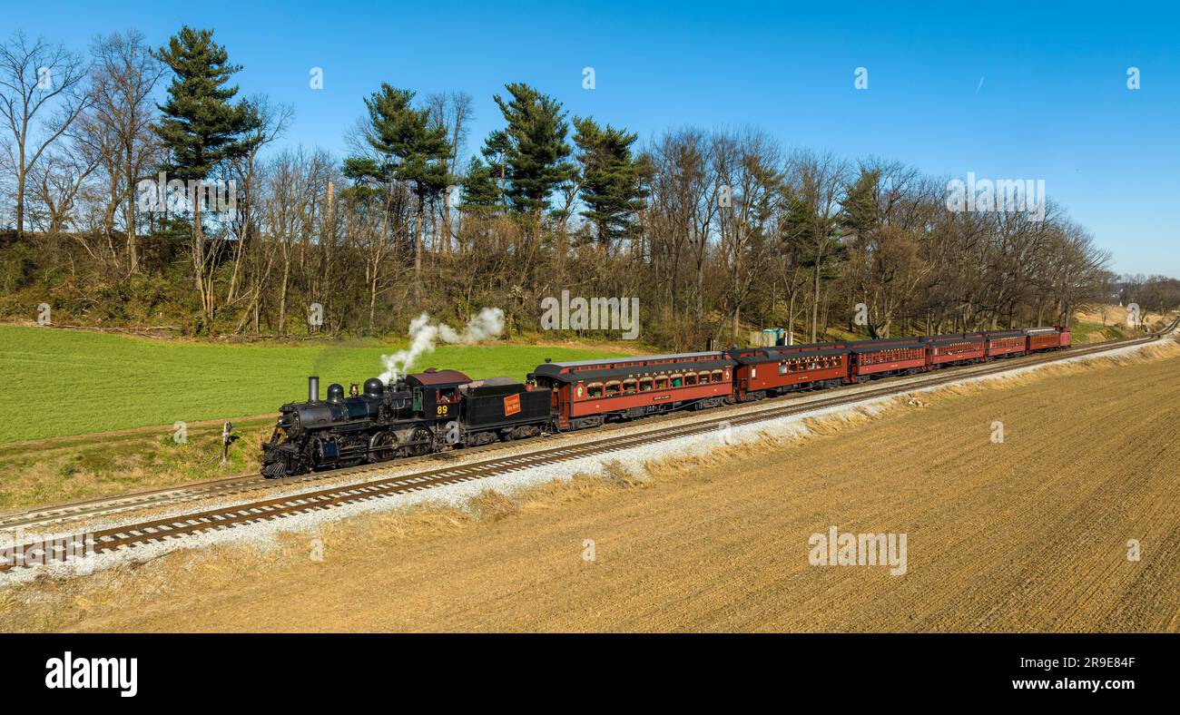 Ronks, Pennsylvania, 26. November 2022 - A Drone View of a restaurated Steam Passenger Train Traveling Thru Farmlands, die zu einer kleinen Station fahren Stockfoto