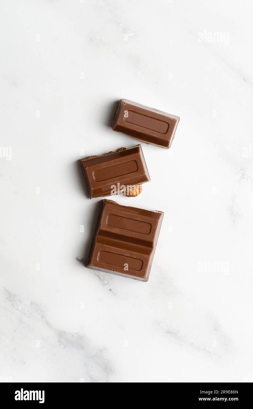 Milchschokolade mit Mandeln auf Marmorhintergrund. Vertikales Format. Stockfoto