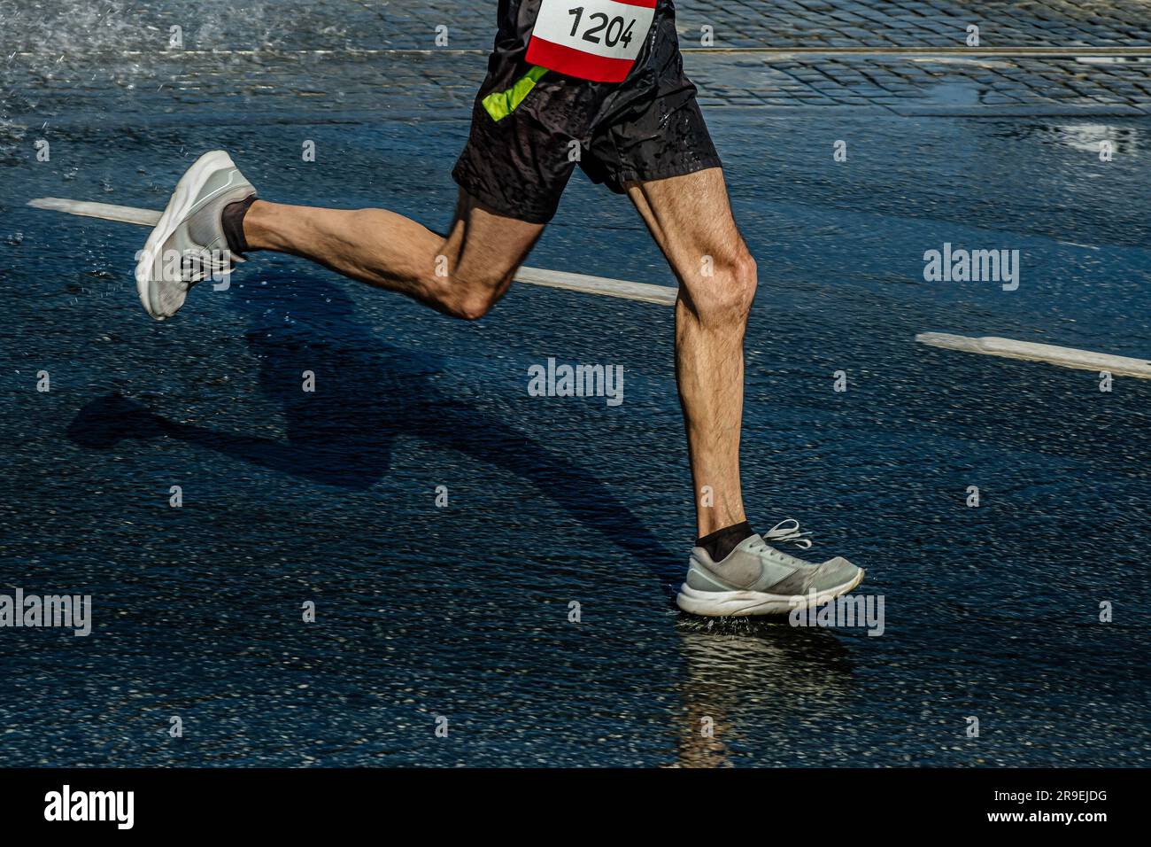 Beine männlicher Läufer läuft Marathonrennen in der Pfütze, sportliche Sommerspiele Stockfoto