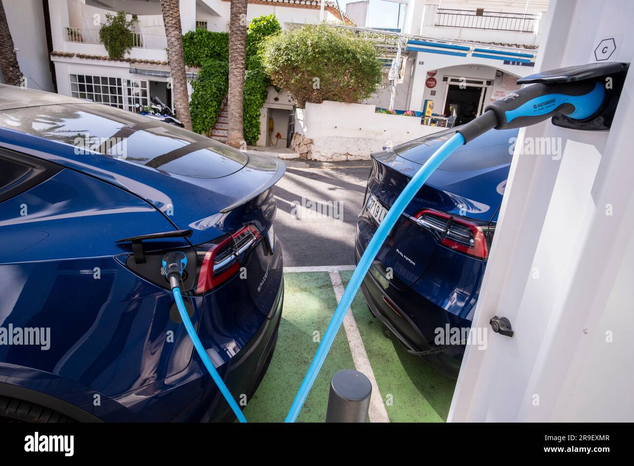 Zwei Elektrofahrzeuge von Tesla, die an einer Ladestation im Dorf Altea La Vella, Alicante, Spanien, aufgeladen werden. Stockfoto