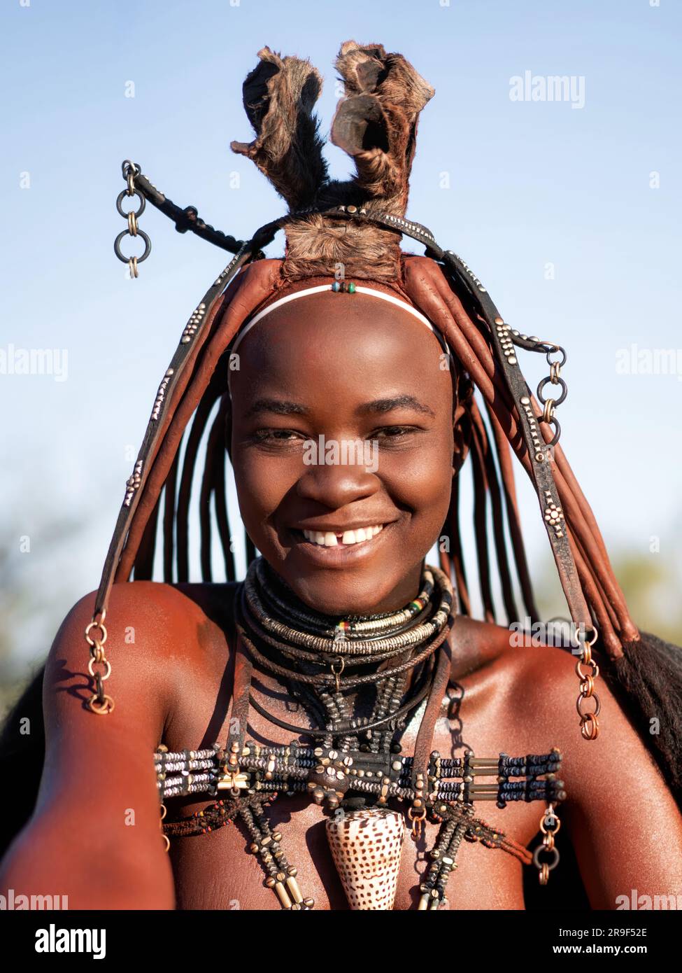 Fröhliche lächelnde Himba-Frau, gekleidet im traditionellen Stil in Namibia, Afrika. Stockfoto