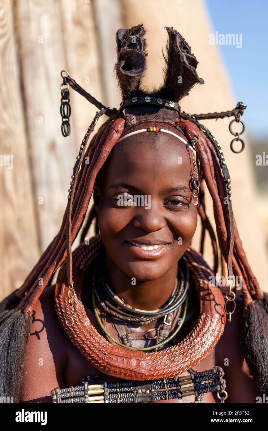 Fröhliche lächelnde Himba-Frau, gekleidet im traditionellen Stil in Namibia, Afrika. Stockfoto