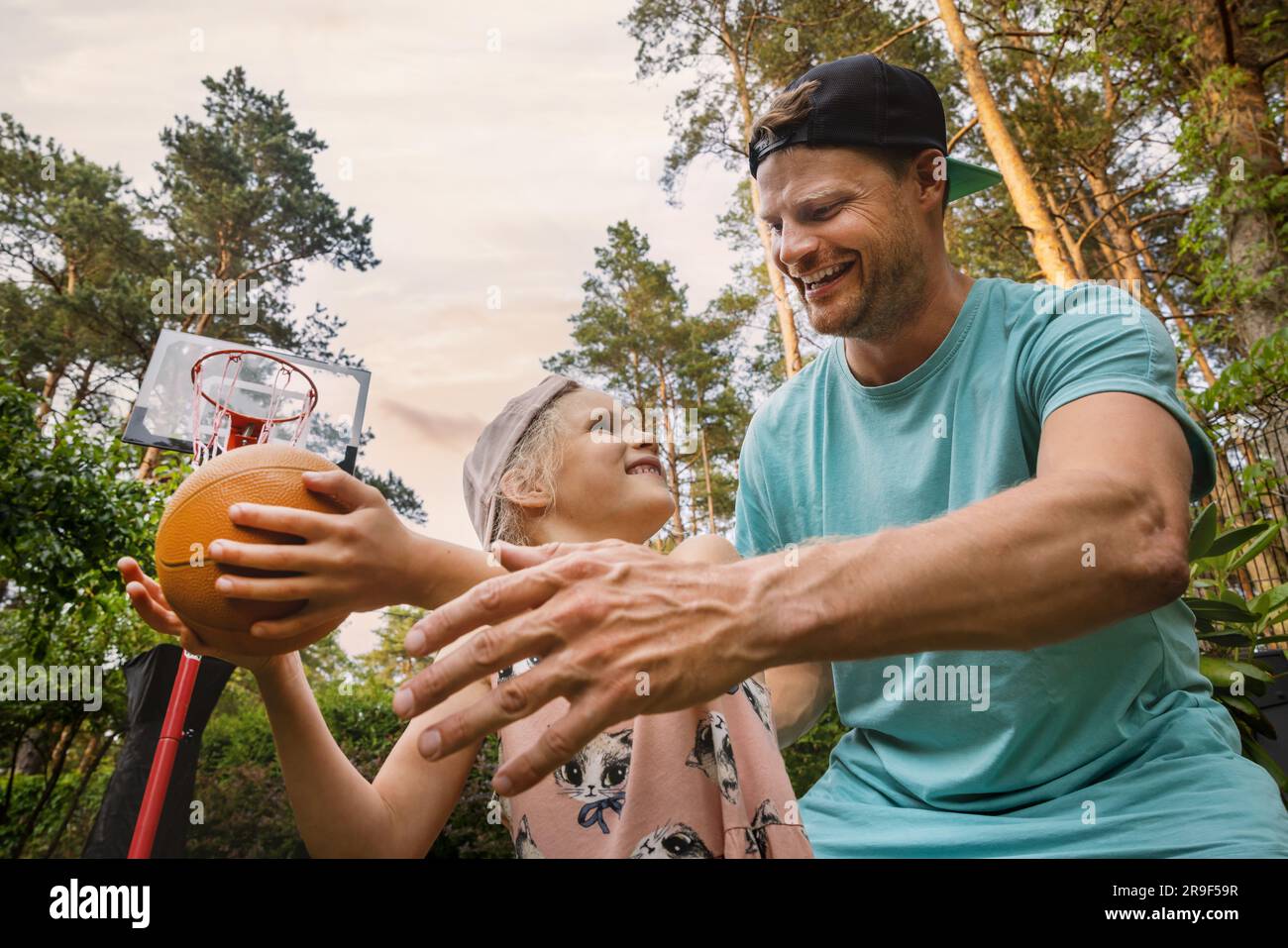 Vater und Tochter spielen Basketball im Hinterhof. Aktive Familie, die Spaß hat und Zeit miteinander verbringt Stockfoto