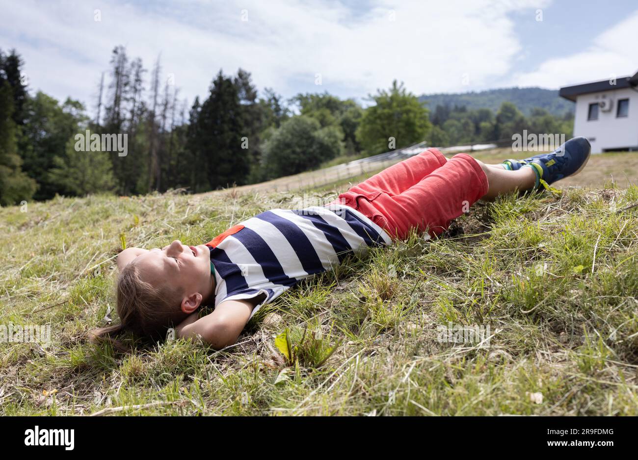 Ein lächelnder Junge im Alter von 7 Jahren liegt auf dem Gras