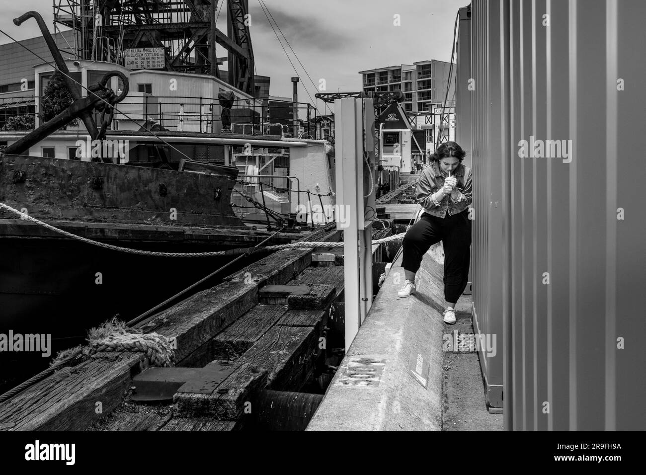 Eine junge Frau nimmt eine heimliche Zigarette hinter einem Container in der Hafengegend von Wellington, New Zealand Capital City. Foto: Rob Watkins Stockfoto