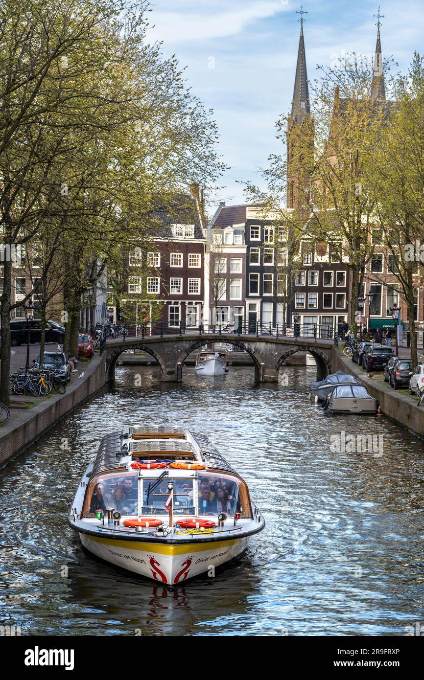 grachtenboot in der Jordaan Gegend von Amsterdam mit den Posthoornkerk Türmen in der Ferne Stockfoto