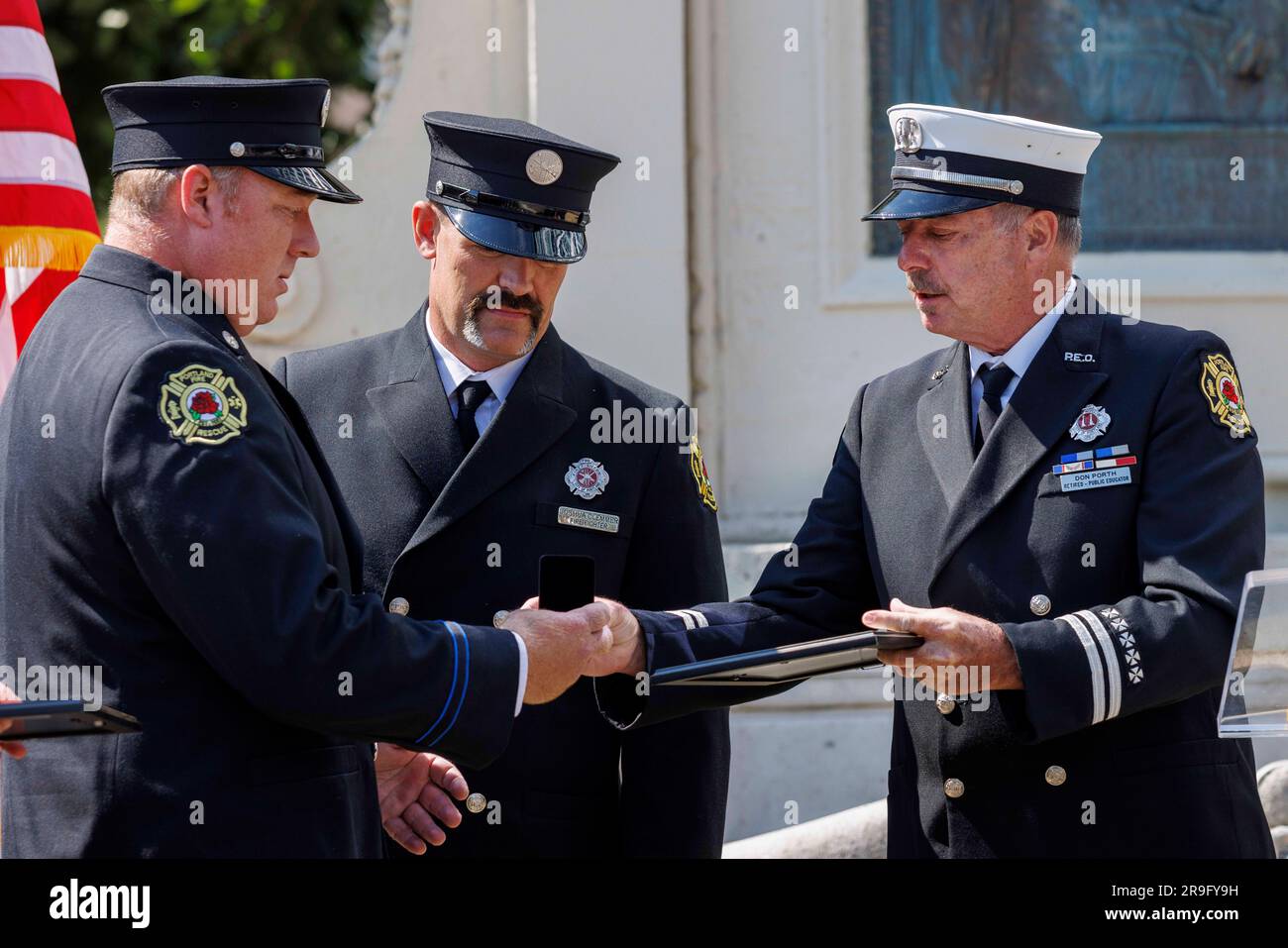 Portland, USA. 26. Juni 2023. Der pensionierte Feuerwehrmann Don Porth, Vorsitzender der historischen Gesellschaft des Bureau, überreicht den David R. Kingsley Silver Award für Valor an die Feuerwehrleute Josh Singleton und Chris Clemmer. Die Feuerwehrleute von Portland feierten am 28. Juni 2023 im Firefighters Memorial im Zentrum von Portland, Oregon, ihre jährliche David Campbell Memorial-Zeremonie zu Ehren der Feuerwehrleute, die im Einsatz ums Leben kamen. Es ist nach dem Feuerwehrchef David Campbell benannt, der am 26. Juni 1911 beim Schutz anderer Feuerwehrleute starb. (Foto: John Rudoff/Sipa USA) Guthaben: SIPA USA/Alamy Live News Stockfoto