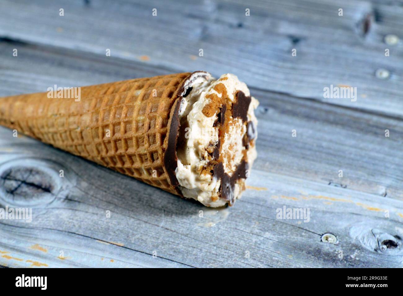 Karamellisierter Keks Eiscreme aus Kakao, Schokolade und Vanillekonus mit Keksstücken und Nüssen in knusprigen Waffelkonus, Schmelzen von kaltem Eis Stockfoto