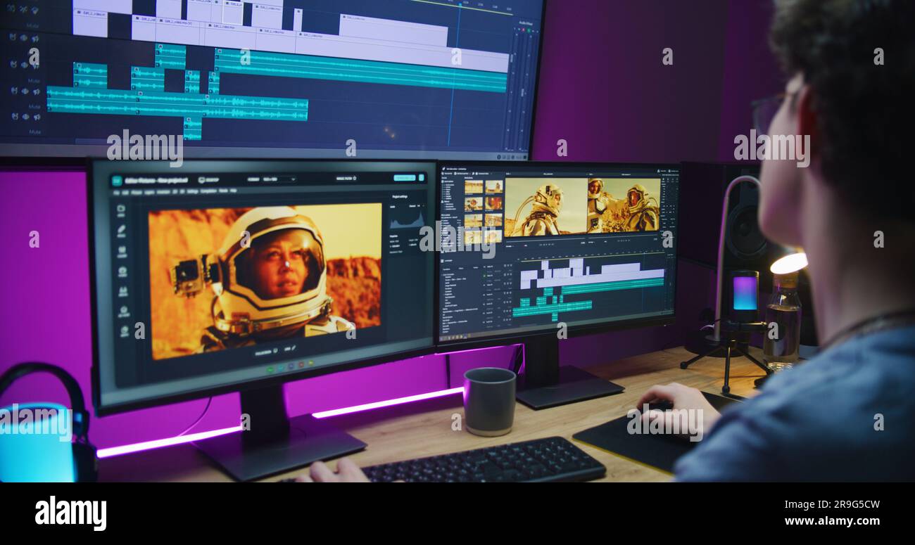 Junger Videofilmer bearbeitet Film über Weltraummissionen, arbeitet im Home Office. Filmmaterial und Software-Schnittstelle mit Tools und Soundtracks auf Computer und großem digitalen Bildschirm. Konzept der Nachbearbeitung. Stockfoto