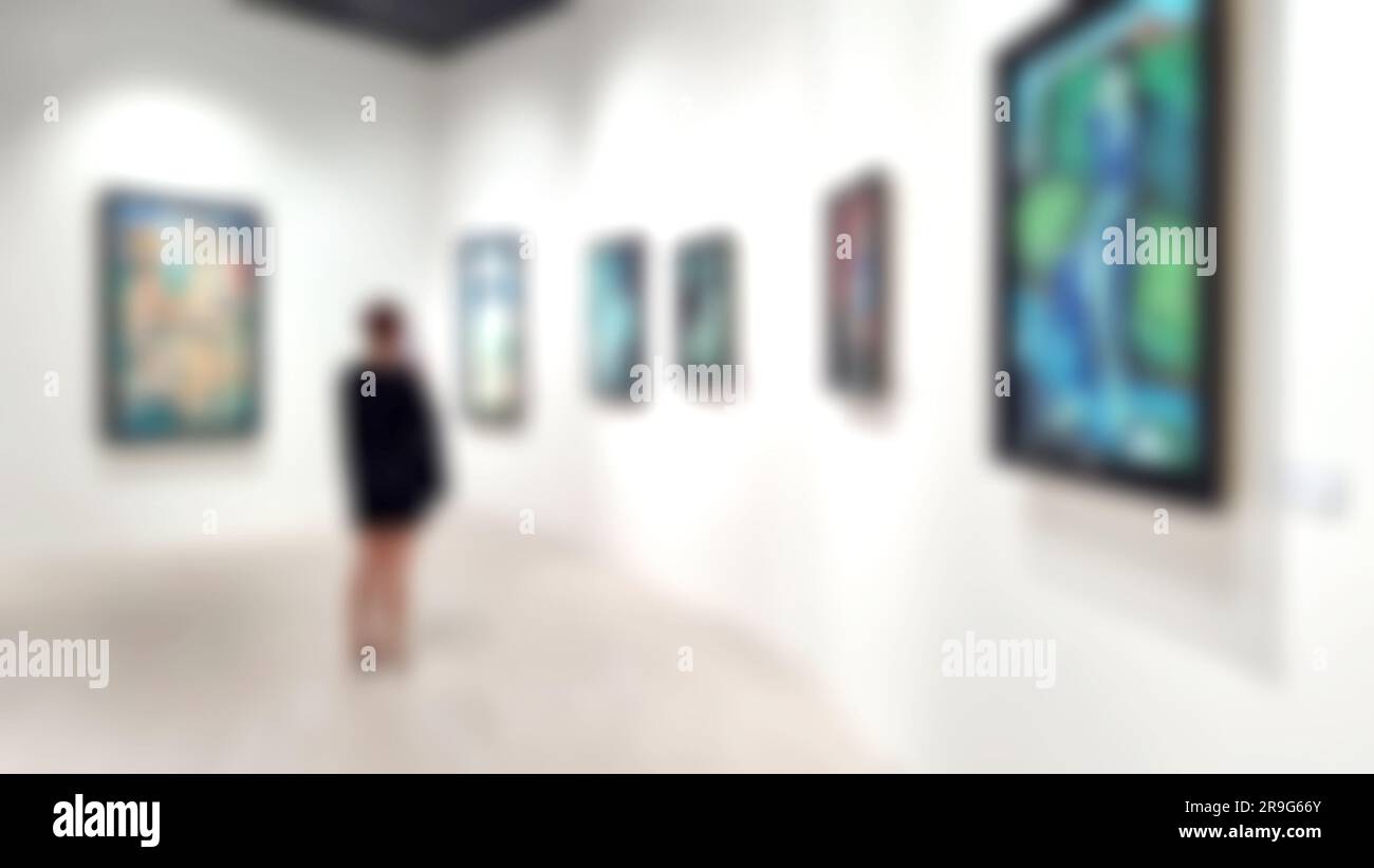 Kunstgalerie mit verschwommenem Hintergrund und Frau, die Gemälde an der weißen Wand ansieht. Stockfoto