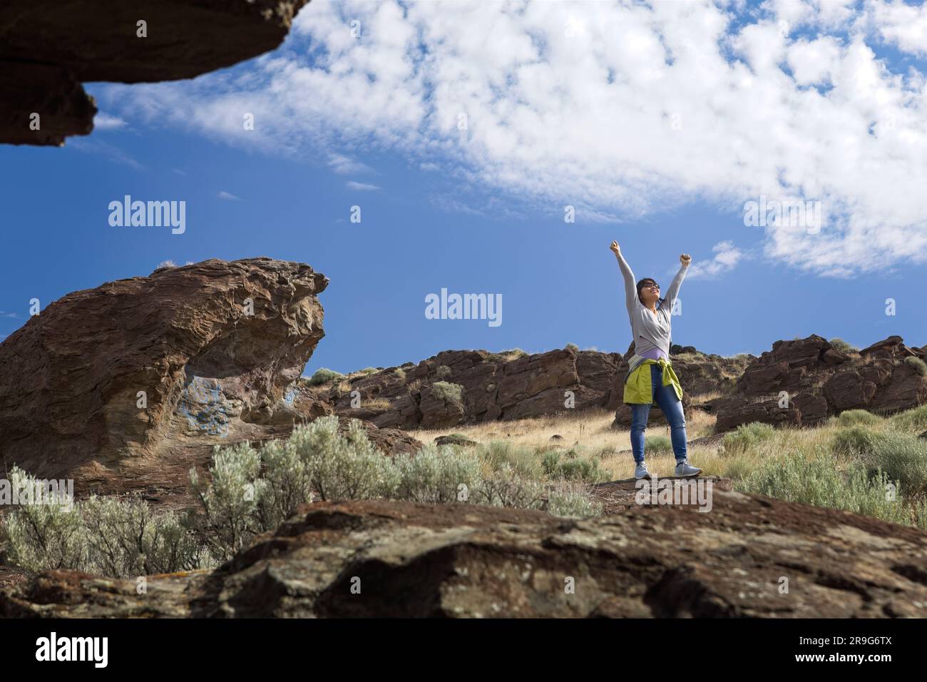 Eine Frau steht mit ausgestreckten Armen und genießt die helle Sonne und die Landschaft in der Nähe von Buhl, Idaho. Stockfoto