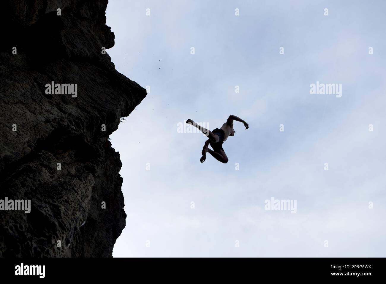 Die Silhouette eines jungen Mannes, der von einem hohen Felsen ins Wasser im Süden Idahos springt. Stockfoto