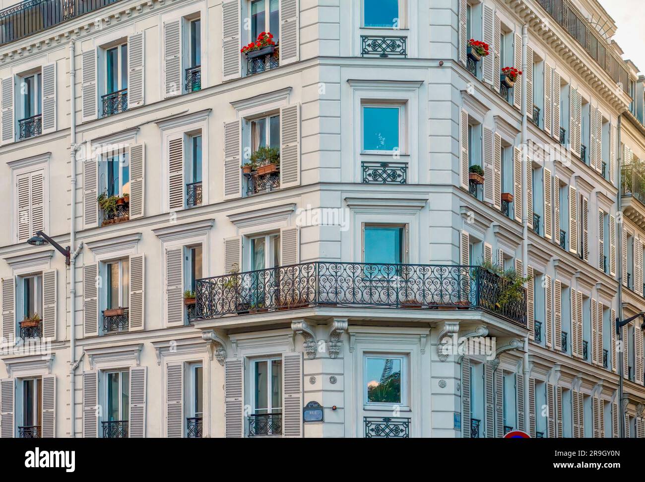 Elegante Fassade eines alten, traditionellen Pariser Apartmentgebäudes mit kunstvoll verzierten schmiedeeisernen Geländern und Fensterläden aus Holz in einem Wohngebiet. Stockfoto