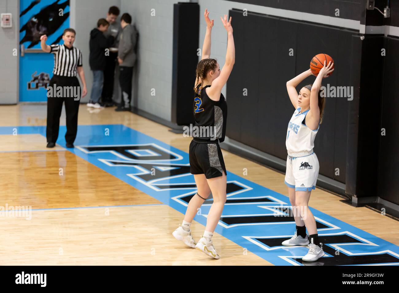 Eine Schiedsrichterin beobachtet, wie ein Lakewood Park Spieler versucht, den Ball während eines Basketballspiels für Mädchen in Auburn, Indiana, USA, zu erreichen. Stockfoto
