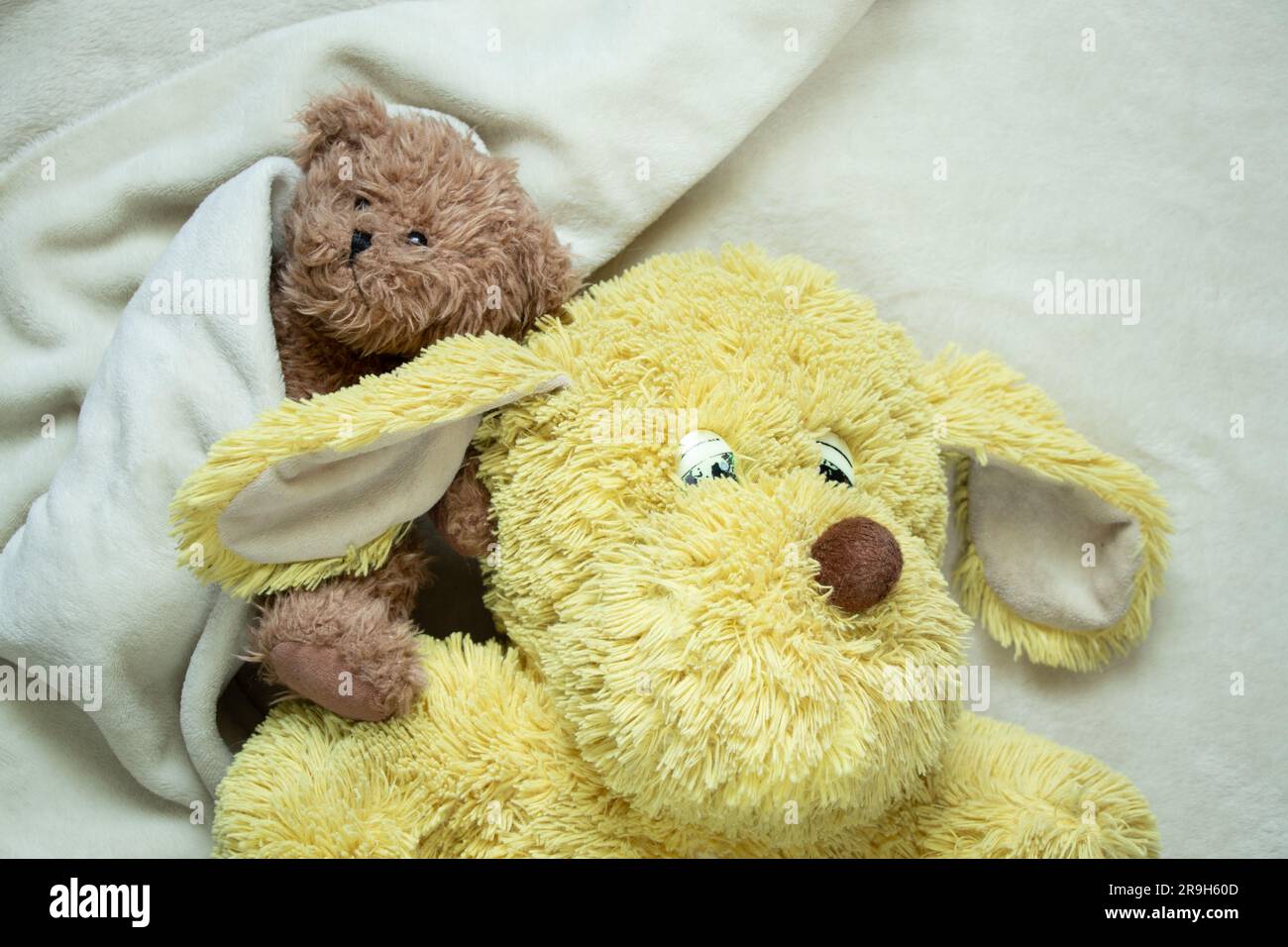 Zwei weiche Kinderspielzeuge liegen auf einer weißen Decke Stockfoto