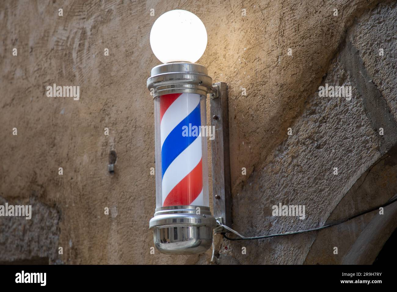 Barber Pole Shop Schild zylindrisch mit Licht rund in alten Friseurwänden weiß rot blau Stockfoto