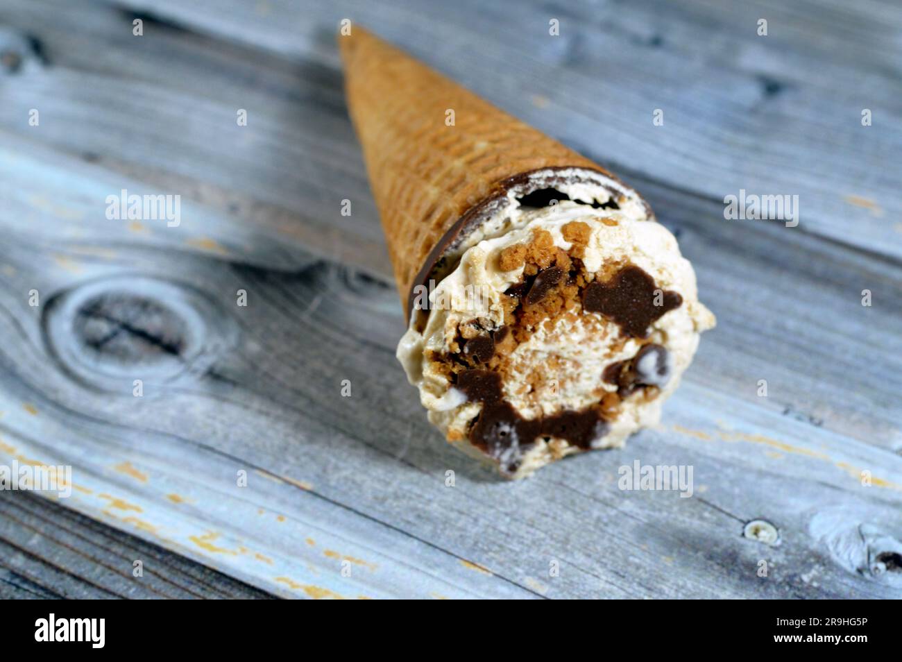 Karamellisierter Keks Eiscreme aus Kakao, Schokolade und Vanillekonus mit Keksstücken und Nüssen in knusprigen Waffelkonus, Schmelzen von kaltem Eis Stockfoto