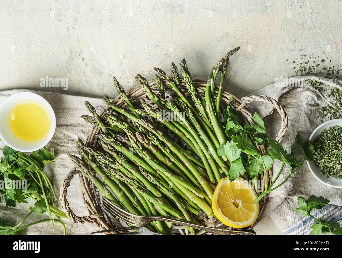 Grüner Spargel mit Kochzutaten: Olivenöl, Zitrone und Kräuter, Draufsicht. Rand Stockfoto