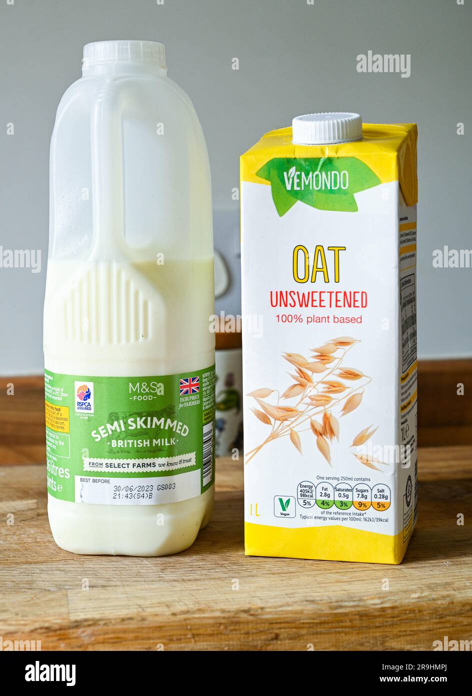 Karton mit teilentrahmter Milch und Karton mit Vemondo ungesüßter pflanzlicher Hafermilch Stockfoto