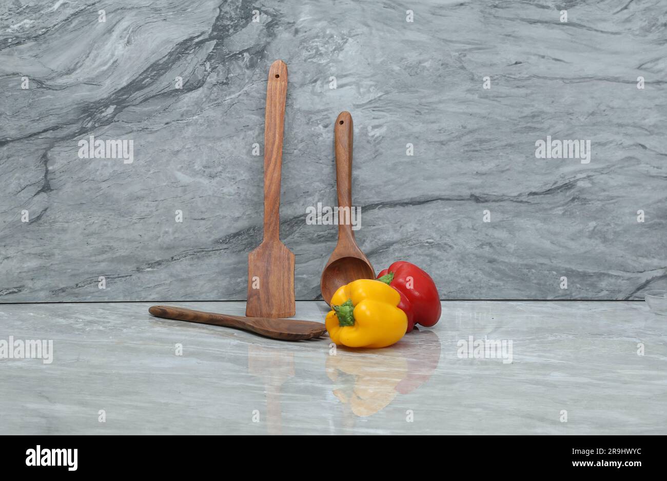 Rot-gelbes Gemüse mit Holzlöffeln auf grauem Marmorhintergrund Stockfoto