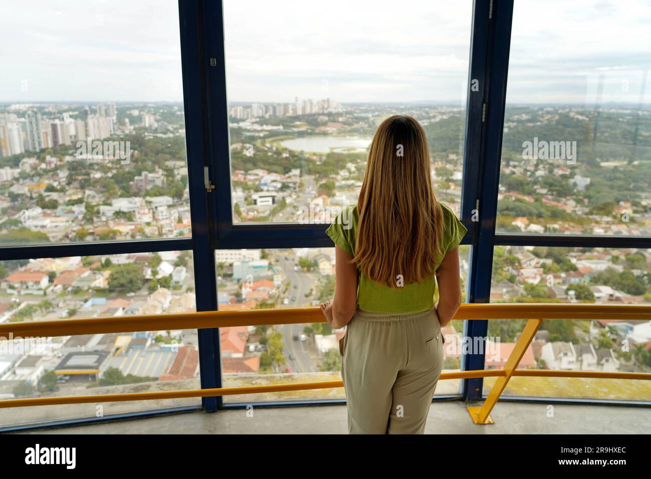Rückblick auf eine junge Frau, die die Stadt Curitiba von Torre Panoramica aus betrachtet, den Panoramaturm von Curitiba, Parana, Brasilien Stockfoto