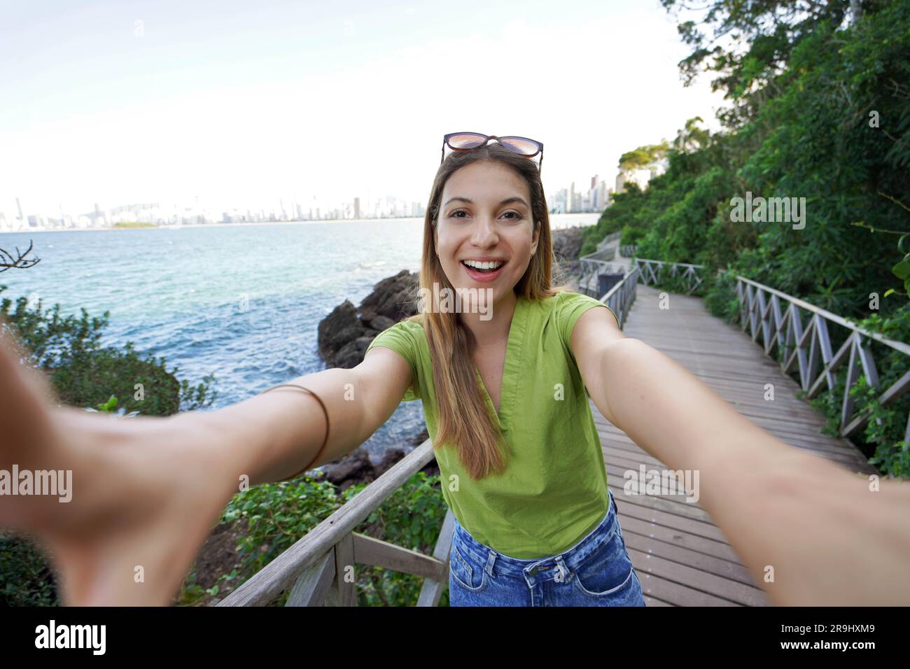 Das coole, lachende Mädchen macht ein Selbstporträt in Balneario Camboriu, Brasilien. Selfie eines jungen, stilvollen Models an der Strandpromenade von Santa Catarina Stat Stockfoto