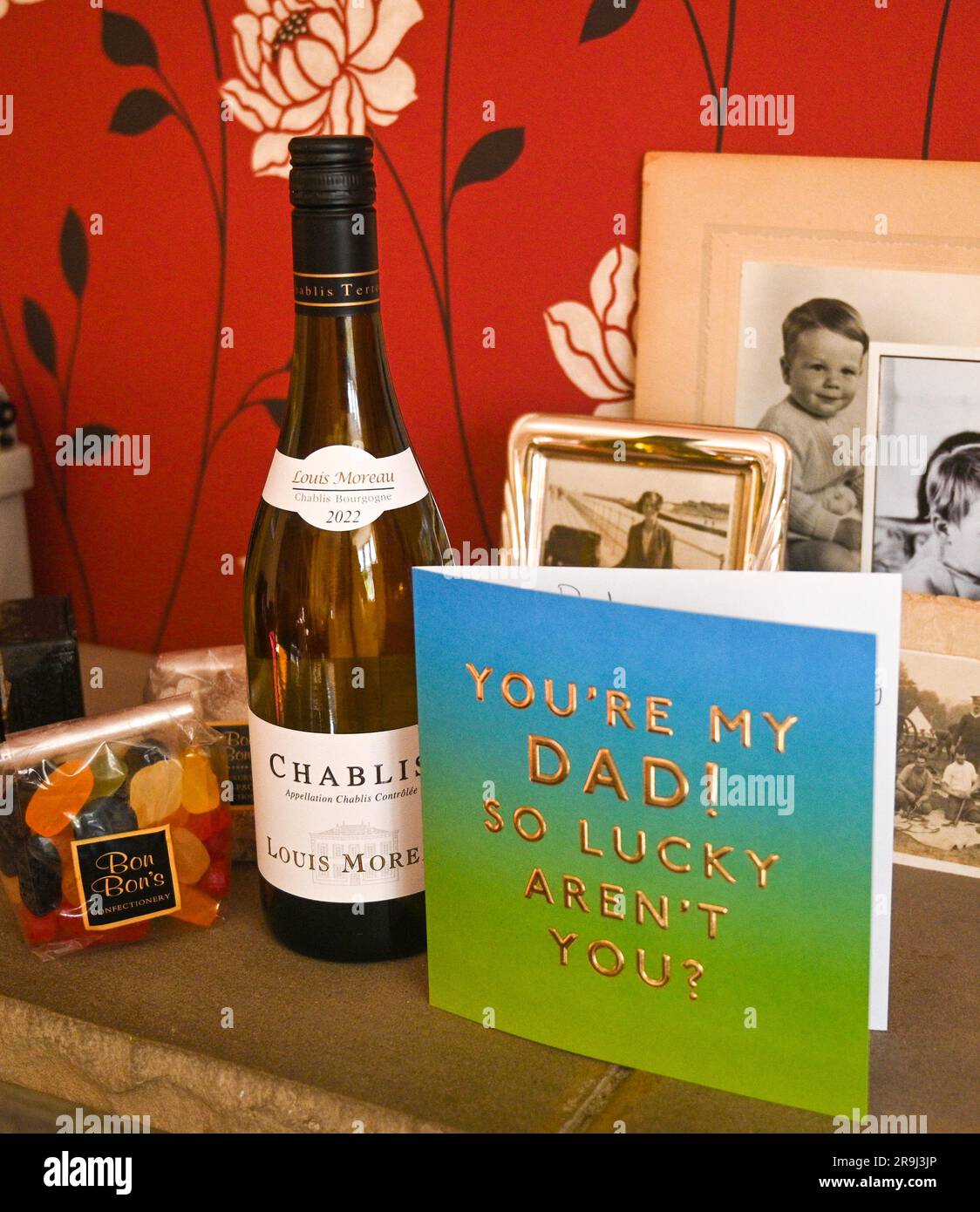 Vatertagskarte und Geschenke von Chablis-Wein und Weingummi mit einigen alten Familienfotos Stockfoto