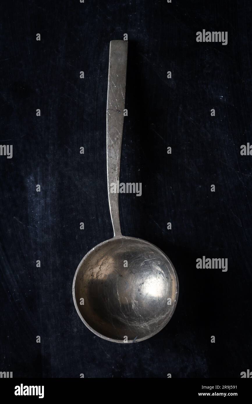 Großer, alter, leerer Löffel auf schwarzem Hintergrund. Flach verlegt. Draufsicht. Speisekonzept. Dunkle Stimmungsfotografie. Stockfoto