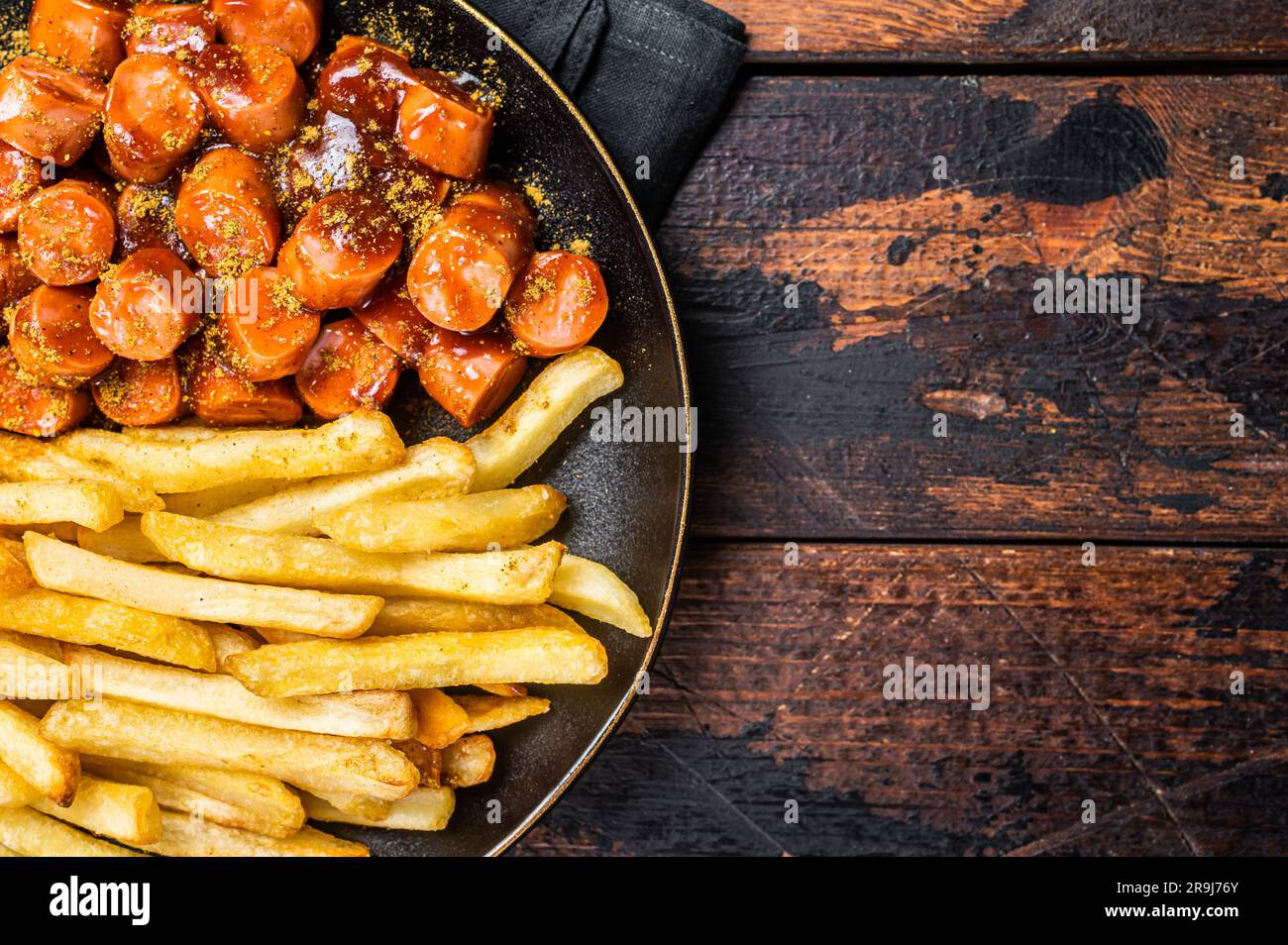 Deutsche Currywurst, Currywurst mit pommes Frites, serviert auf einem Teller. Holzhintergrund. Draufsicht. Stockfoto