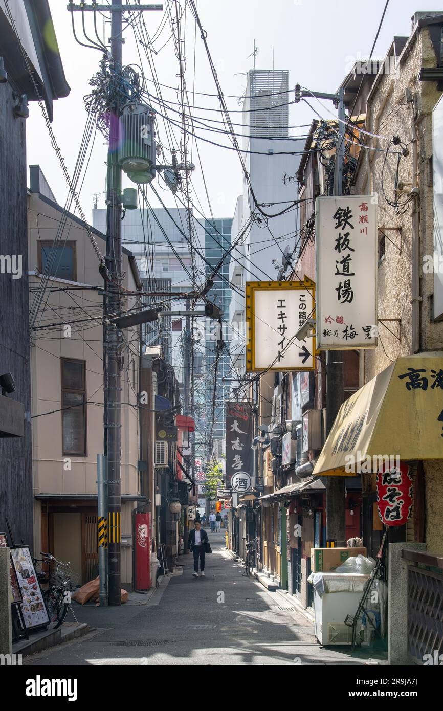 Kyoto, Japan – April 2023; vertikaler Blick auf eine der engen Straßen der Stadt mit traditionellen Gebäuden, Schildern und vielen Stromleitungen, die scheinbar hängen Stockfoto
