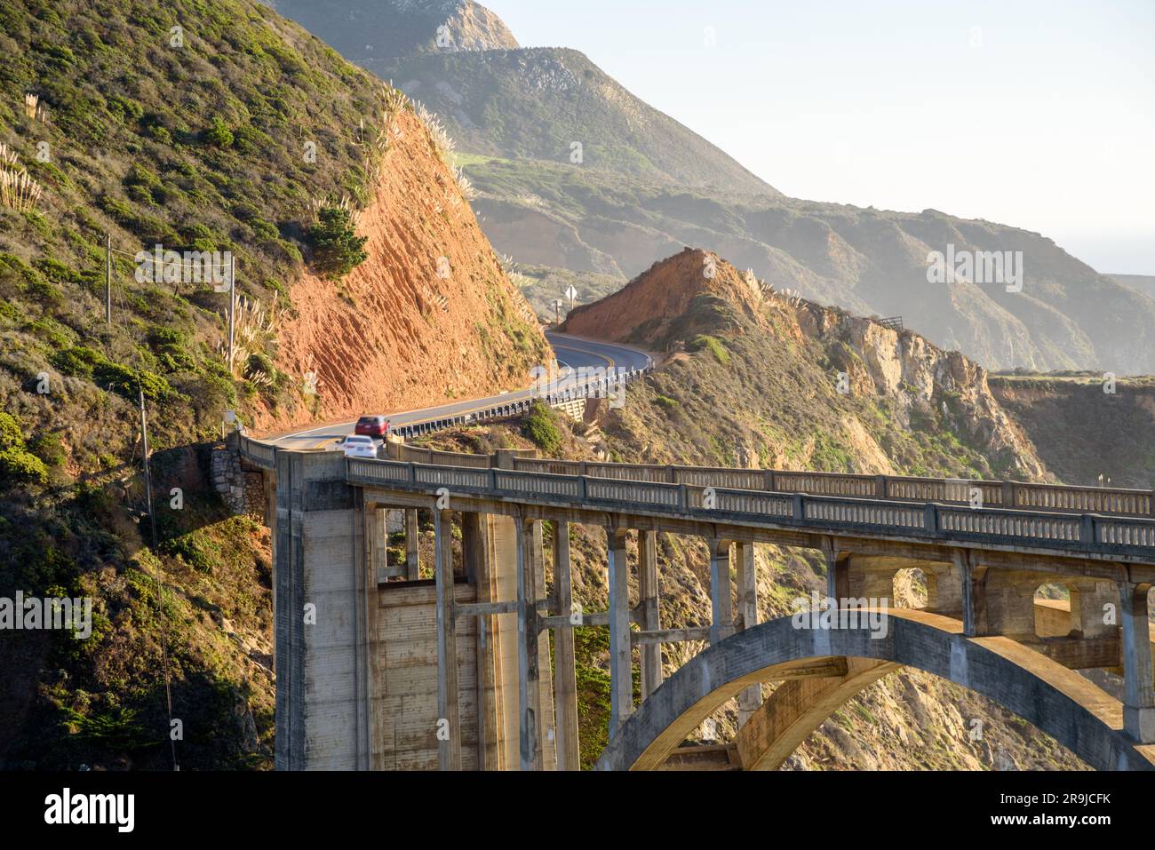 Eine Brückenbrücke aus Beton entlang einer gewundenen Küstenstraße bei Sonnenuntergang im Herbst. Stockfoto