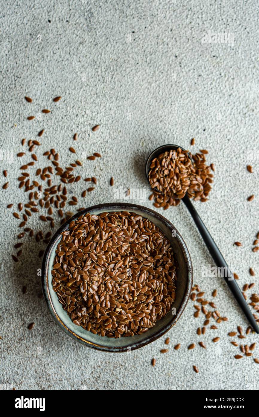 Schüssel mit rohen Leinsamen auf Betontisch Stockfoto