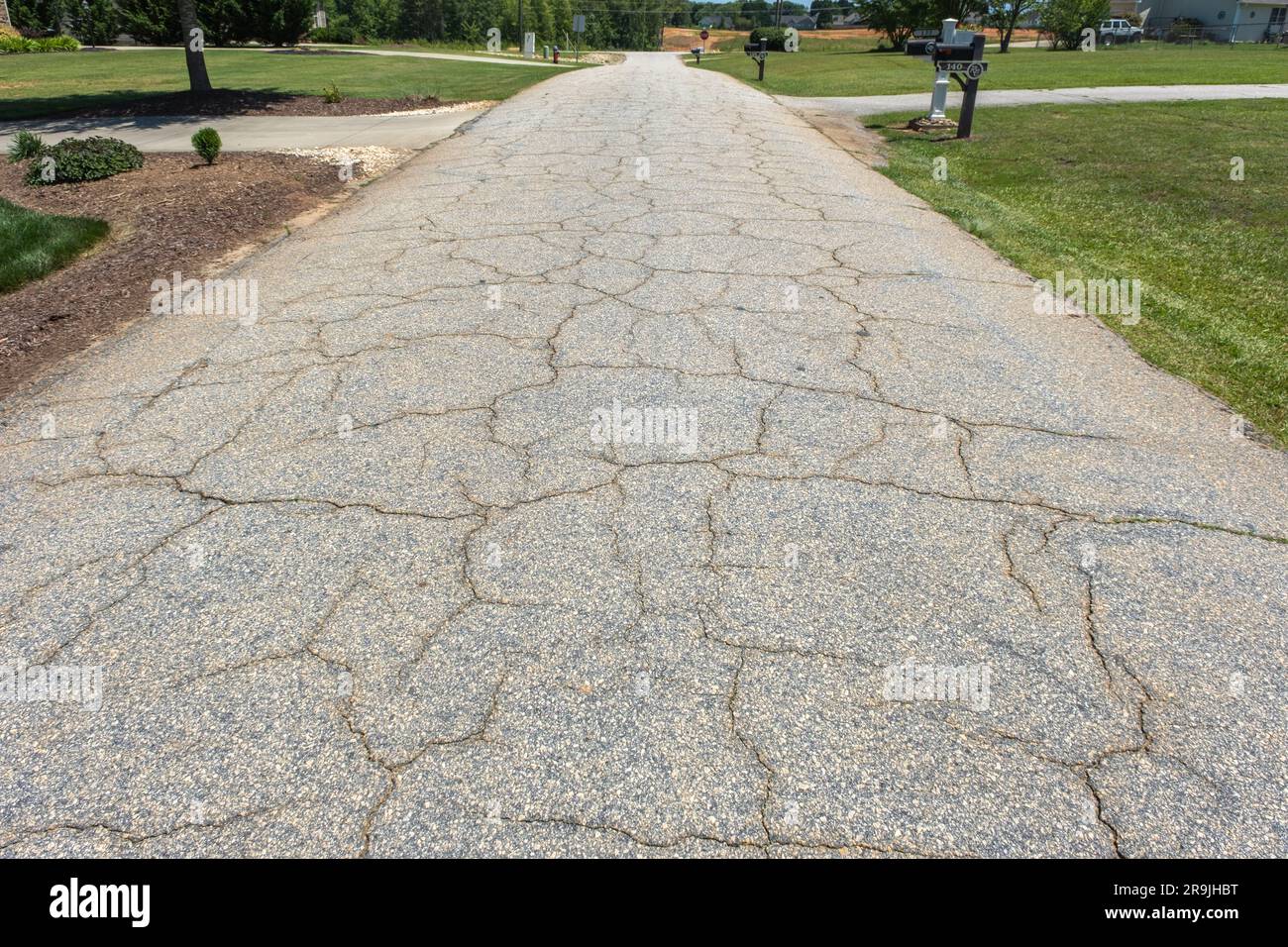 Eine Asphaltstraße in einer Wohngegend ist gerissen und muss repariert werden. Stockfoto