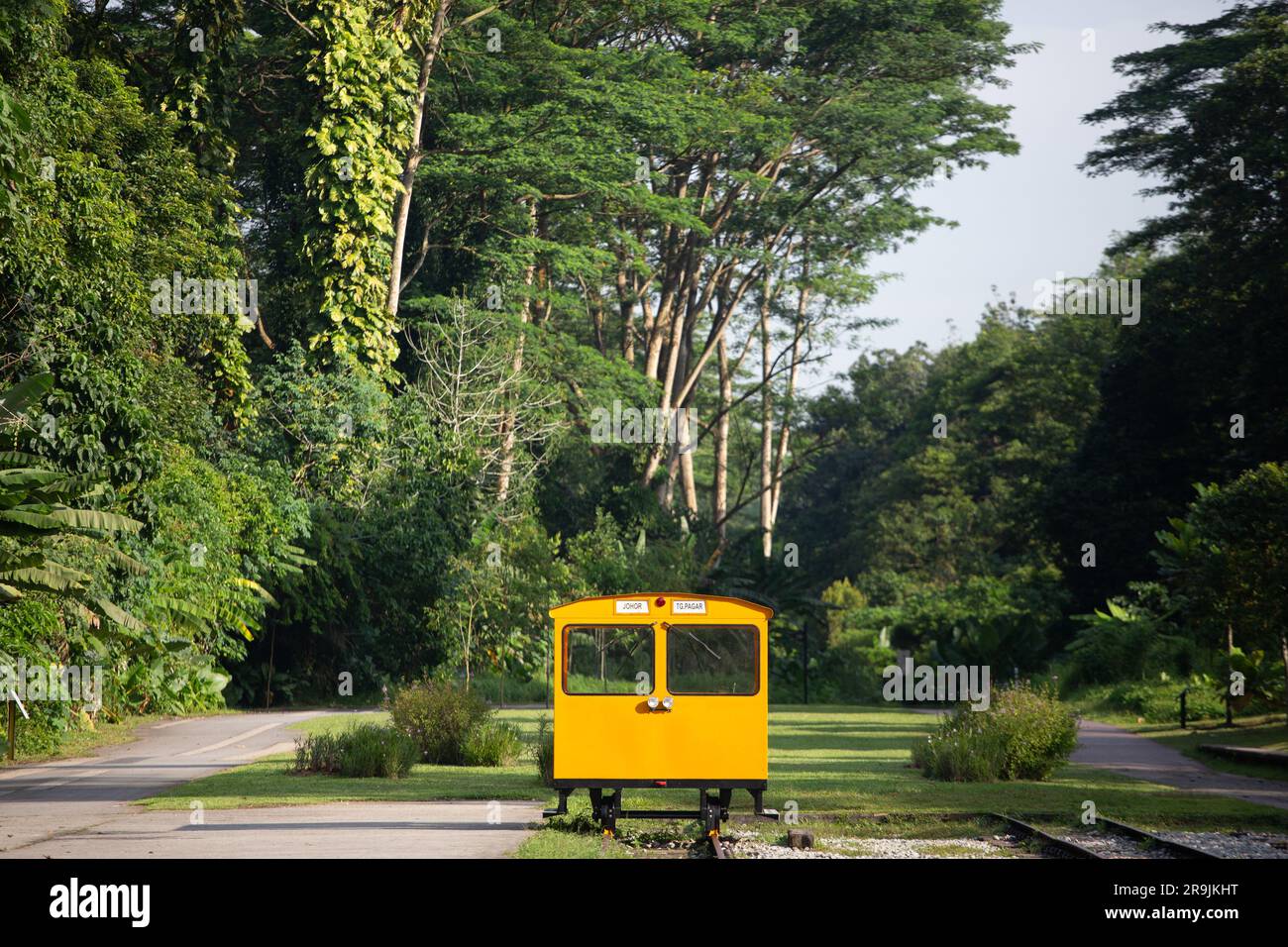 Leuchtend gelbe Servicewagen auf den Bahngleisen vor grünem Hintergrund im Gemeinschaftsbereich des Bahnhofs Bukit Timah. Singapur. Stockfoto